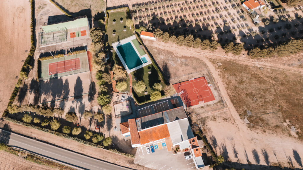 Vista aérea del club con instalaciones deportivas, piscina y zonas de recreo.